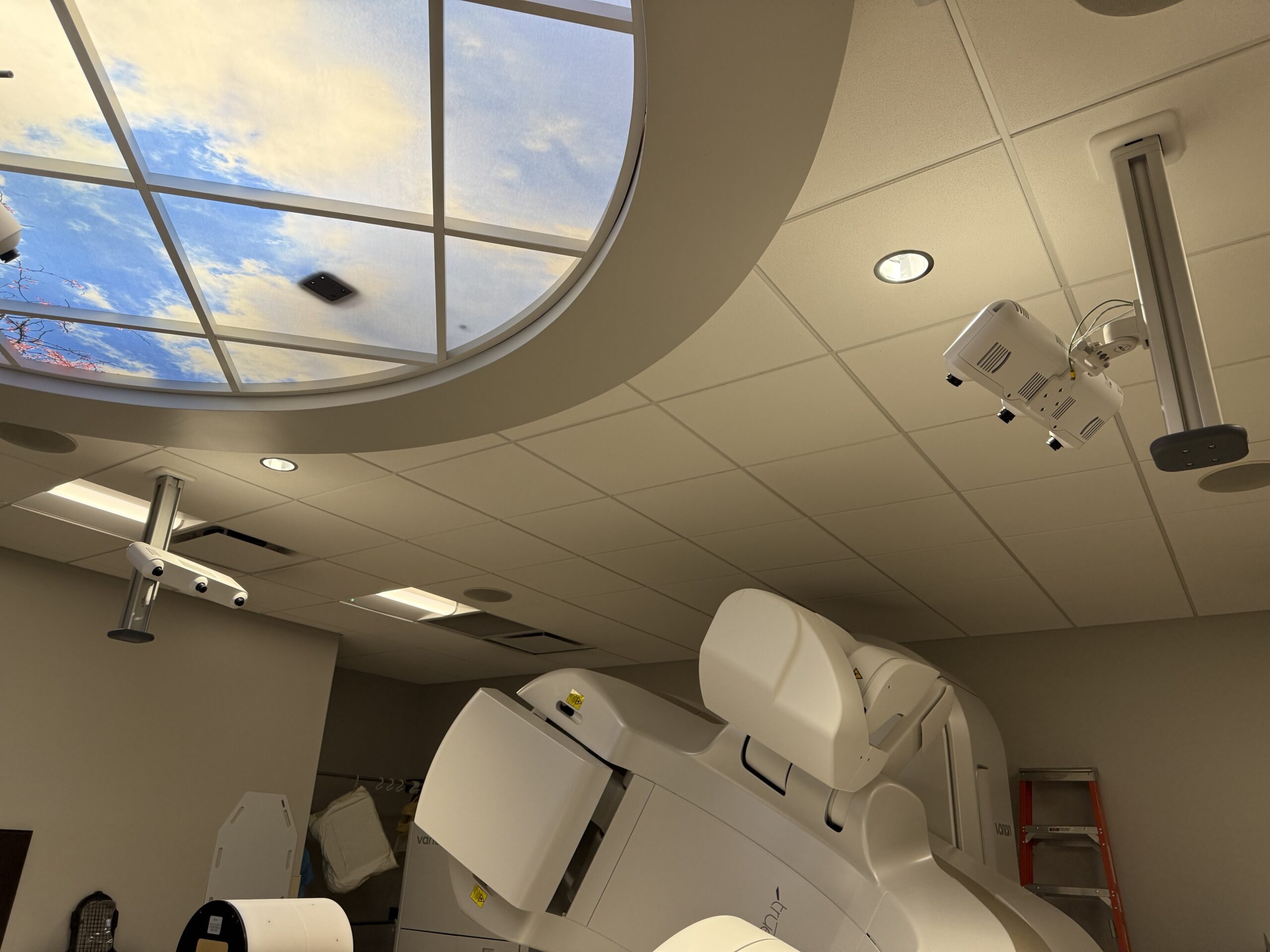 A clinician beside a linear accelerator in a treatment vault